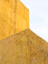 Rough plastered painted yellow wall and blue sky