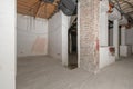 Rough premises with all exposed unfinished electrical piping and cement floors, brick pillars and half-plastered walls