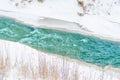 Rough river at the foot of the mountains in a turquoise, blue, green forest in winter, ice and snow around the landscape. Royalty Free Stock Photo