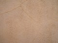 Rough sandy textured beige painted wall surface with fine cracks