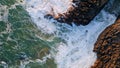 Rough sea waves washing seashore stones. Top drone view ocean crashing on rocks