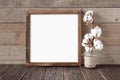 Rough square wooden frame with cotton branch on wooden background Royalty Free Stock Photo