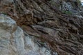 Rough stone light textured rock, beige brown cliff with grass. Different layers of slabs. Cloudy. Baikal Royalty Free Stock Photo