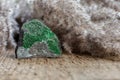 Rough stone with uvarovite crystals over wood