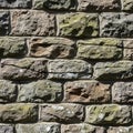 Rough stone wall with rectangular bricks of varying earthy tones, including brown, gray, and green. Royalty Free Stock Photo