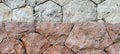 Rough stone wall with a striking horizontal split: light grey rocks meet rustic reddish ones. Textured contrast Royalty Free Stock Photo