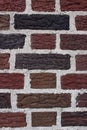 Rough texture and pretty patterns in old weathered red, brown, and black brick wall