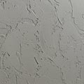 Rough textured gray plaster wall with an uneven surface, featuring various irregular Royalty Free Stock Photo
