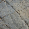 Rough-textured rock surface with a network of intersecting cracks and fissures. Royalty Free Stock Photo