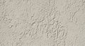 Rough-textured wall with uneven plaster surface, beige color. The texture features irregular bumps Royalty Free Stock Photo