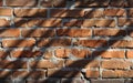 Roughly built red brick wall covered in shadow