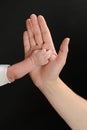 Roughness and texture on the skin of the palm of the hand of a Caucasian person against the hand of a baby. Hands isolated on blac