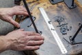 Roulette and pencil. Screws on the table in the workshop. The hands of a wood master. Metal table legs. Desktop. Working process.