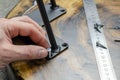 Roulette and pencil. Screws on the table in the workshop. The hands of a wood master. Metal table legs. Desktop. Working process.