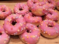 Pink polka dotted glazed donuts in pile on cutting board