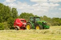 A round baler discharges a hay bale during harvesting Royalty Free Stock Photo