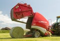 A round baler discharges a hay bale during harvesting Royalty Free Stock Photo