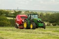 A round baler pulled by a John Deere during harvesting Royalty Free Stock Photo