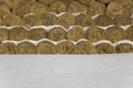Round bales of dry yellow hay lie in rows under the snow Royalty Free Stock Photo