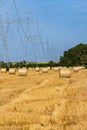 Round bales of straw in an endless field under high-voltage line VL-750. High-voltage line VL-750 on metal supports goes Royalty Free Stock Photo