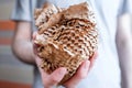 Round ball of brown paper in hand. Thin mesh of brown paper. Side view, vivid picture