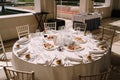 Wedding dinner table reception. Round banquet table with white tablecloth and cream chiseds Chiavari. Dishes are on the Royalty Free Stock Photo