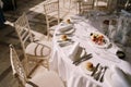 Wedding dinner table reception. Round banquet table with white tablecloth and cream chiseds Chiavari. Dishes are on the Royalty Free Stock Photo