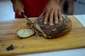 Round black bread  with a ruddy crust on a wooden board in the kitchen cut with a large knife Royalty Free Stock Photo