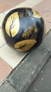 A round black object with a gold pattern on the side of the roads