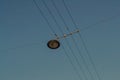 Round black pendant glass lamp hanging from lines wires over city road in blue sky in sun