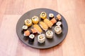 Round black plate with sushi mix, maki with cucumber, Norwegian salmon nigiri and surimi, white rice Royalty Free Stock Photo