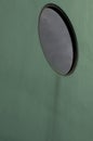 A round black window in a green wall Royalty Free Stock Photo