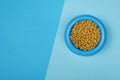 Round Blue food bowl with cat kibble seen from a high angle view