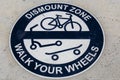 Round blue and white Dismount Zone - Walk Your Wheels sign painted on sidewalk - Grungy and view from top