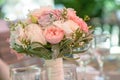 Round bridal bouquet featuring pastel color peonies and roses, lace and greenery, set in a transparent vase