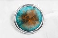 Round brooch with hand-colored silk batik on gray Royalty Free Stock Photo