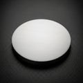 A round brushed metal disk placed on a textured black surface Royalty Free Stock Photo