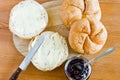 Round buns, butter and currant jam on a wooden tray background.