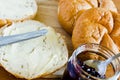 Round buns, butter and currant jam on a wooden tray background.