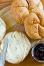 Round buns, butter and currant jam on a wooden tray.