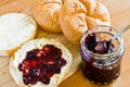 Round buns, butter and currant jam on a wooden tray.