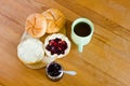 Round buns, butter, jar with currant jam and cup of tea.