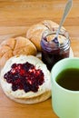 Round buns, butter, jar with currant jam and cup of tea.