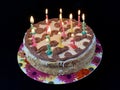 Round cake with candles, on a black background. A sweet birthday present for a teenager. A festive dessert for the whole family