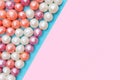 Round candies in glaze. Candy pearls. White, orange and purple. Pink and blue background. Flat lay. Top view. Copy space