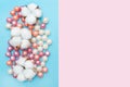 Round candies in glaze and cotton flowers. Candy pearls. White, orange and purple. Pink and blue background. Flat lay