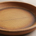 A round ceramic plate with a textured surface features earthy brown and beige tones, Royalty Free Stock Photo