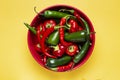 Round ceramic red cup with a set of hot chili peppers, top view, on yellow Royalty Free Stock Photo