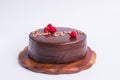 A round chocolate cake with raspberry decor and the inscription - Bon appetit. On a wooden stand isolated on a white background. Royalty Free Stock Photo