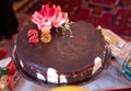 There are red flowers and rings on it . A dark chocolate tort . Round chocolate cake. 25 year old candle .